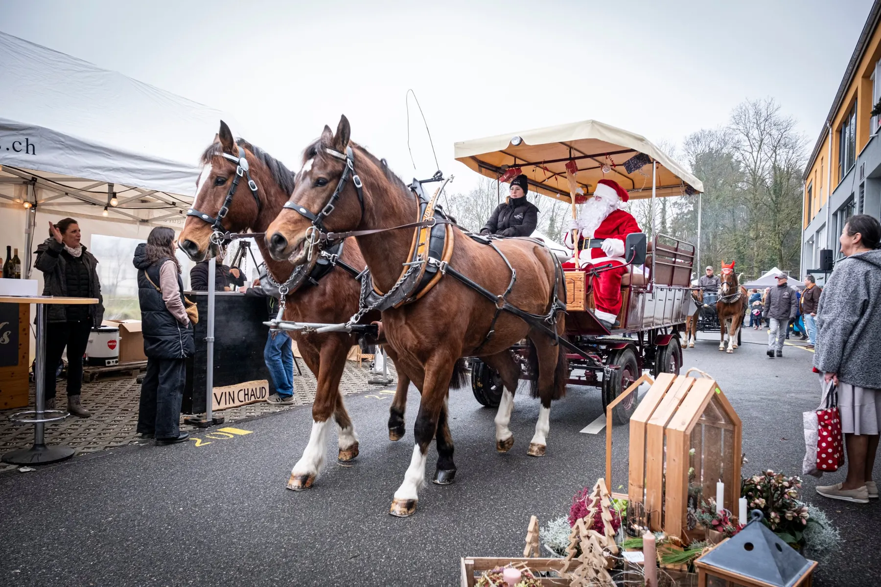 Le Père Noël arrive en calèche tirée par deux chevaux au milieu du marché